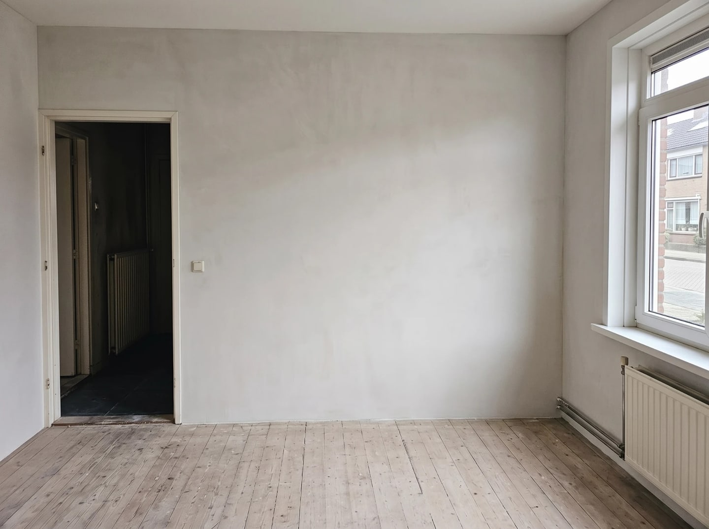 Dezelfde woonkamer met strak glad stucwerk op muren en plafond